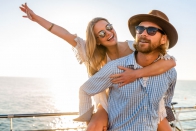 attractive-happy-couple-laughing-traveling-in-summer-by-sea-man-and-woman-wearing-sunglasses