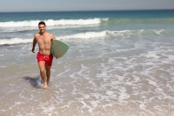 shirtless-man-with-surfboard-walking-beach-sunshine